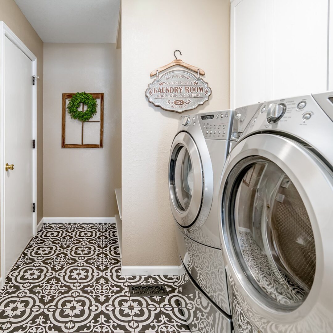 A laundry room with two machines and a tile floor