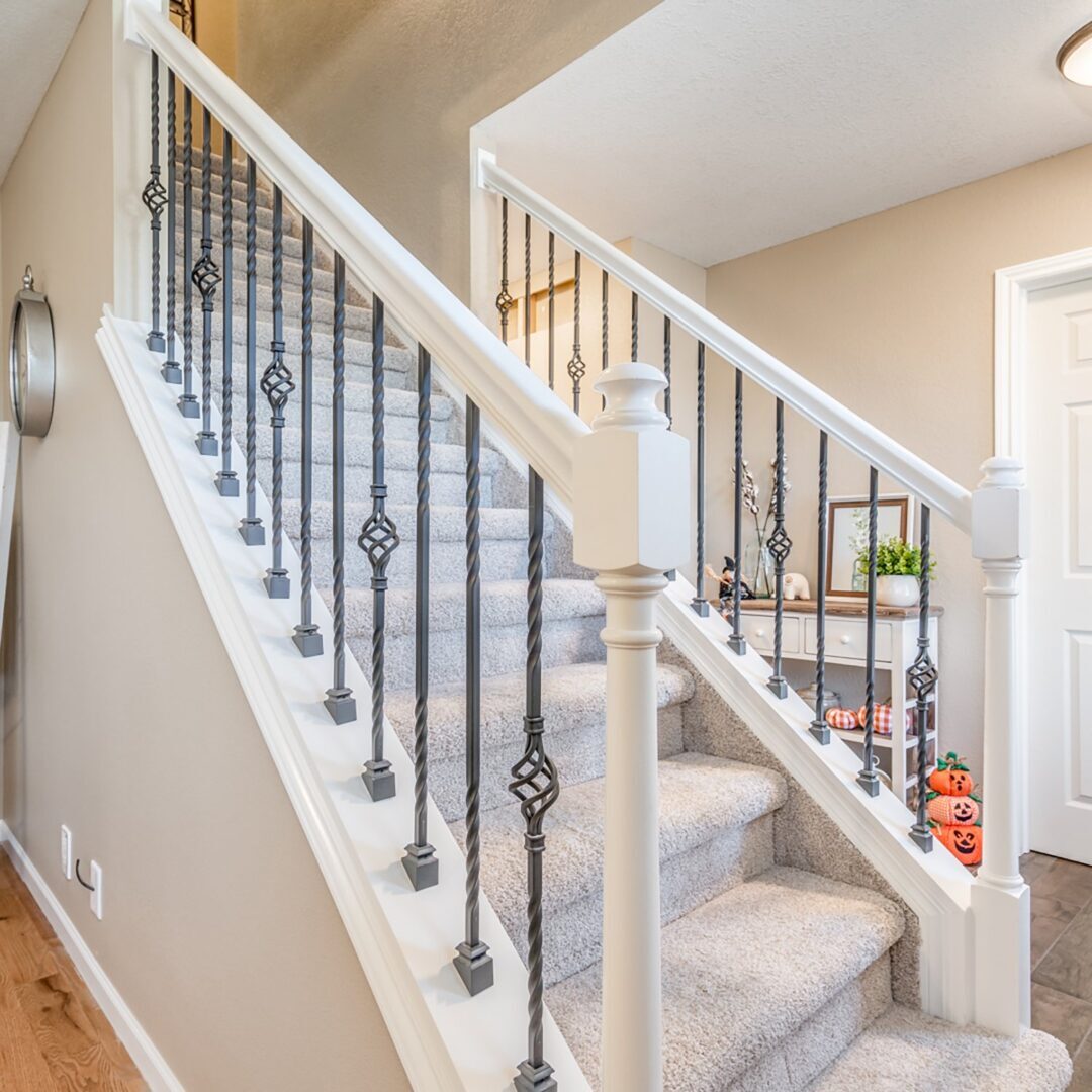 A white staircase with black iron railing and carpet.